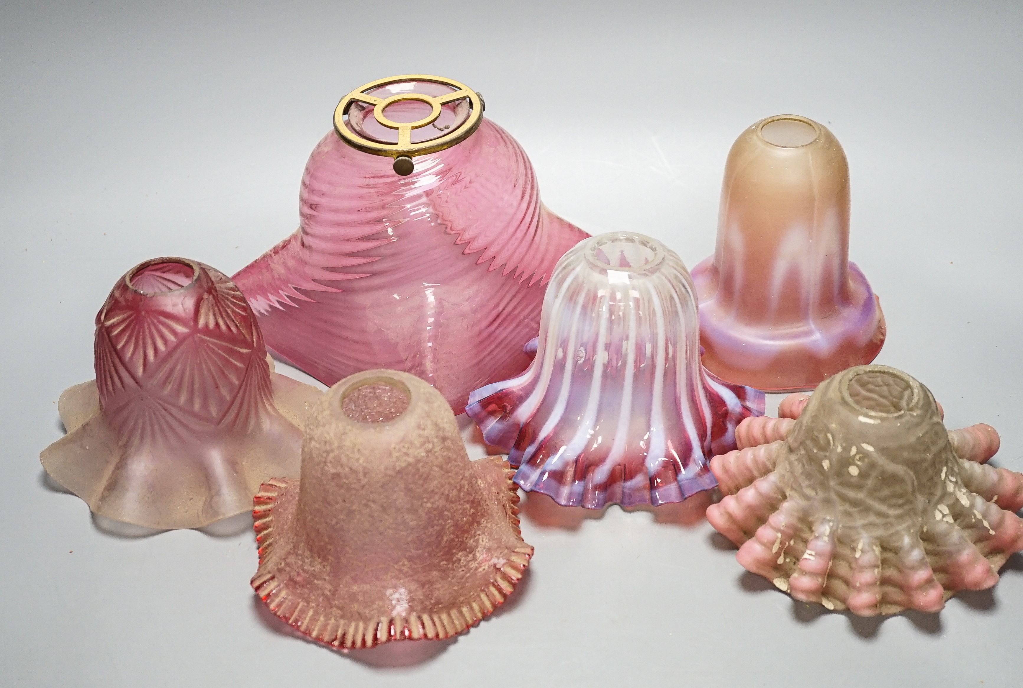 Six various cranberry glass lamp shades, two with opalescence, largest 16 cms high.